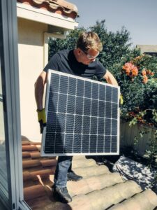 pexels-photo-9875444-9875444 A worker installs a solar panel on a roof, promoting clean and renewable energy.